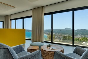 Ein modernes Zimmer mit großen Fenstern, Blick auf eine Küstenlandschaft und einem gelben Raumteiler.