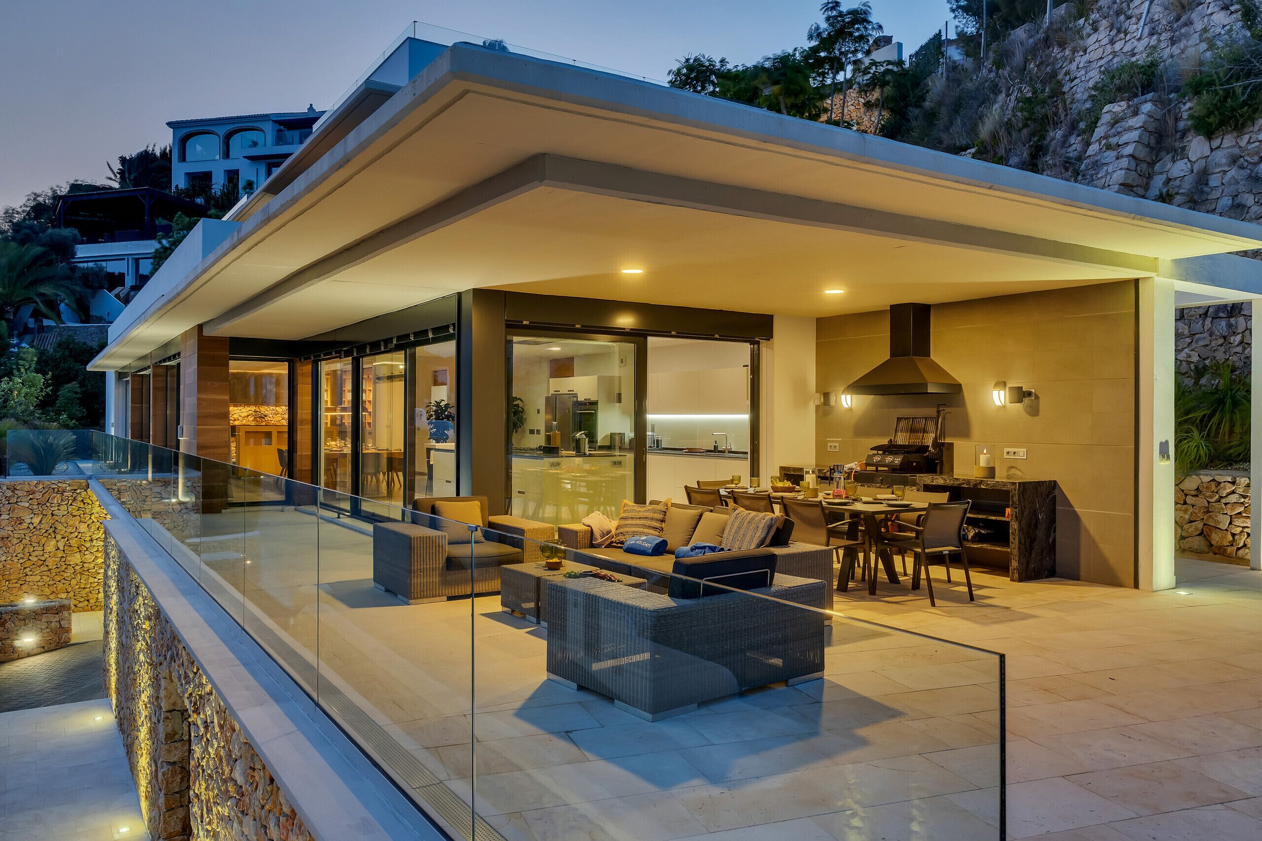A modern house with a covered outdoor area featuring a dining set and seating.
