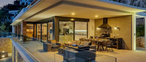 Ein modernes Haus mit überdachter Terrasse, ausgestattet mit Esstisch und Sitzgelegenheit.