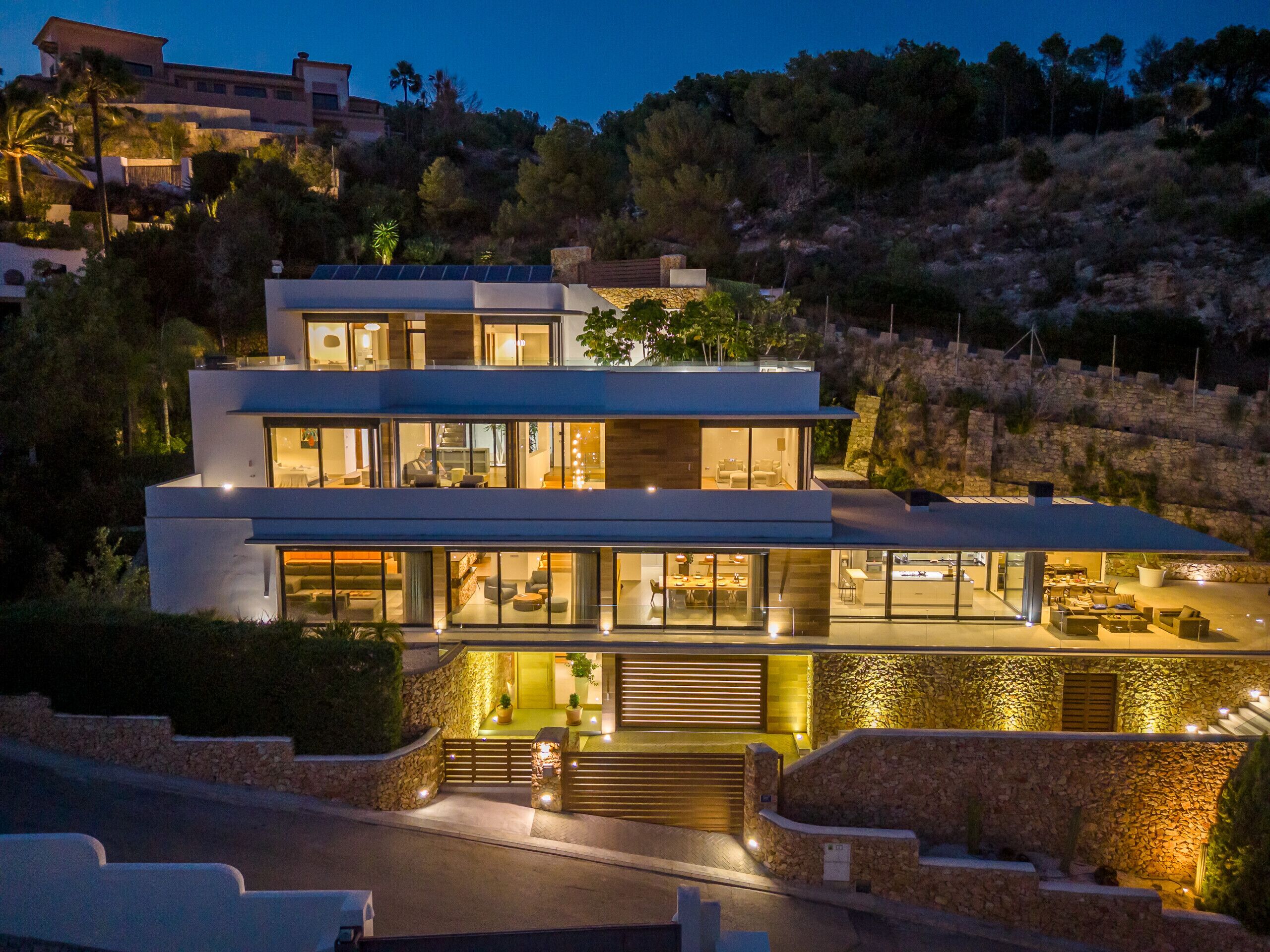 A modern two-story house with large windows, a stone facade, and a landscaped front yard.