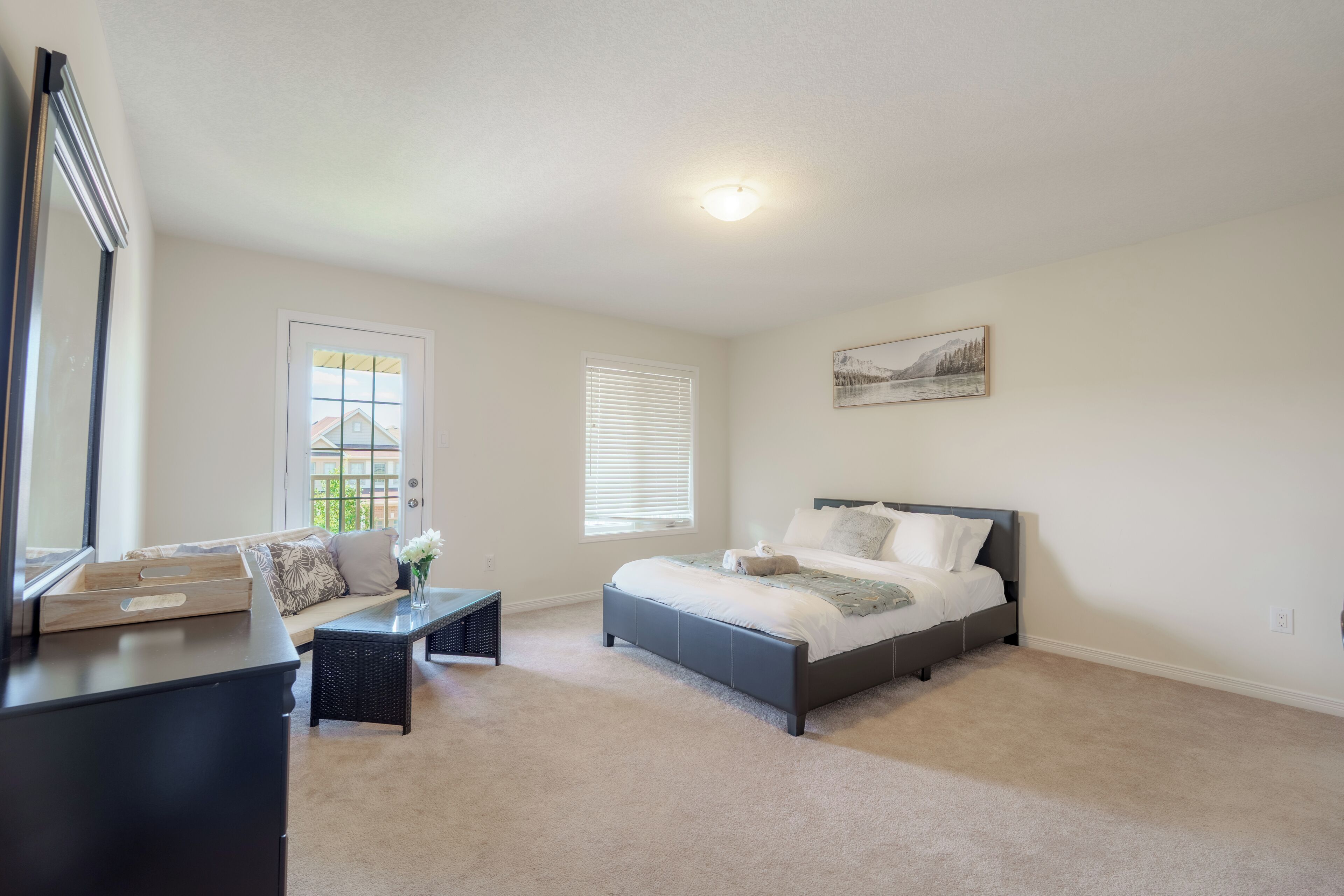 A bedroom with a bed, a desk, a chair, a window, and a painting on the wall.