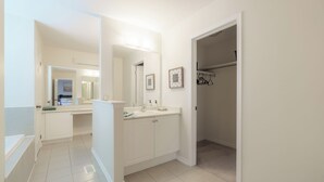 A modern bathroom with a bathtub, a vanity with a sink, and a walk-in closet. - Luxury 4BR Getaway|Mins to Falls & Casino|Sleeps 9 (Niagara Falls)