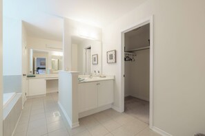 Ein modernes Badezimmer mit Badewanne, Waschtisch und begehbarem Kleiderschrank.