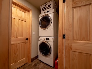 A laundry room with two stacked washing machines and a dryer, wooden doors, and a tiled floor. - Family Cabin with Beautiful view of Bear Lake (Garden City)