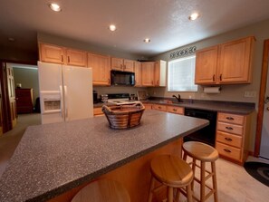A kitchen with wooden cabinets, a granite countertop, a microwave, a refrigerator, and a sink. - Family Cabin with Beautiful view of Bear Lake (Garden City)