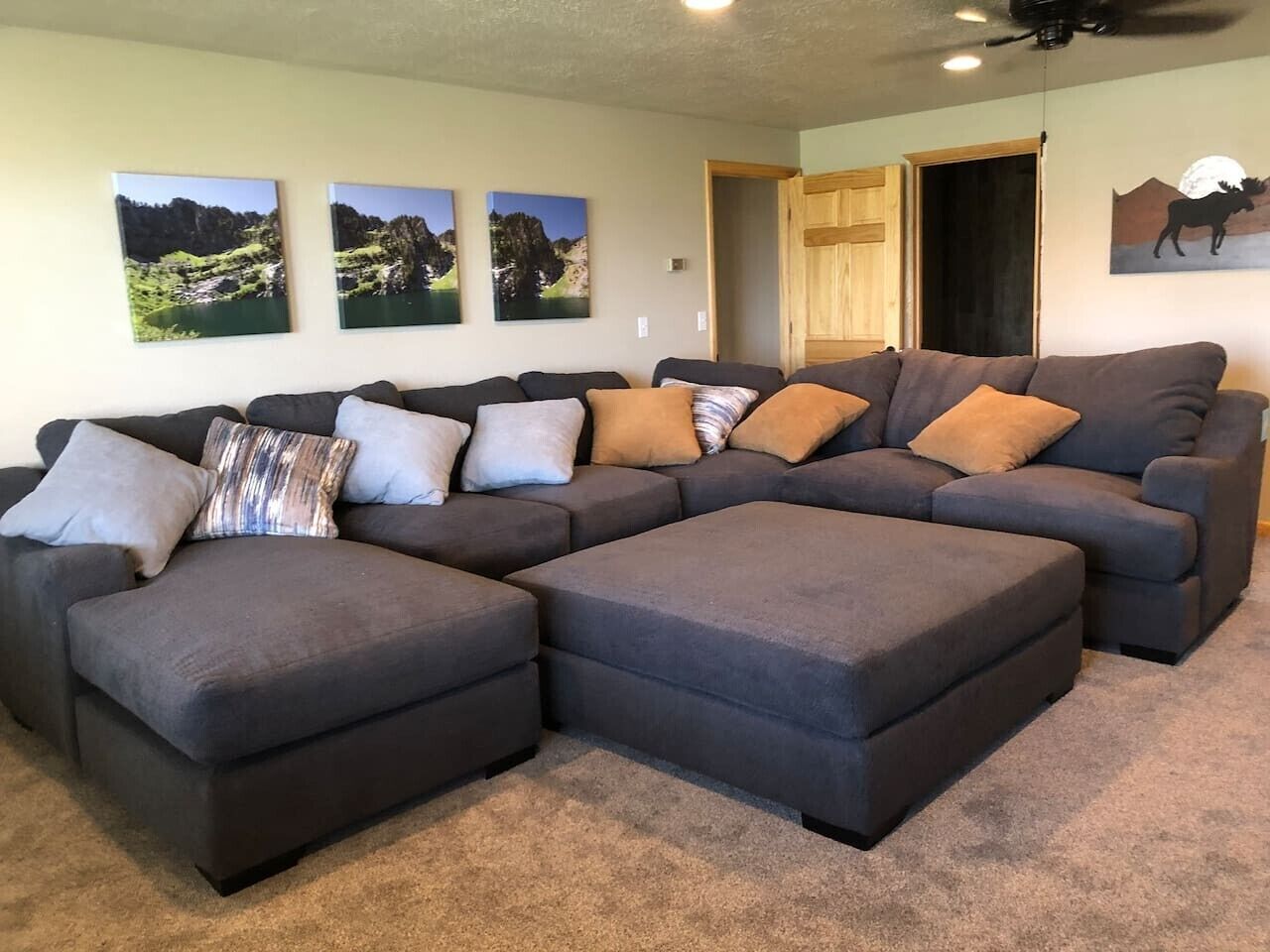 A sectional sofa with multiple cushions and a ceiling fan in a living room.