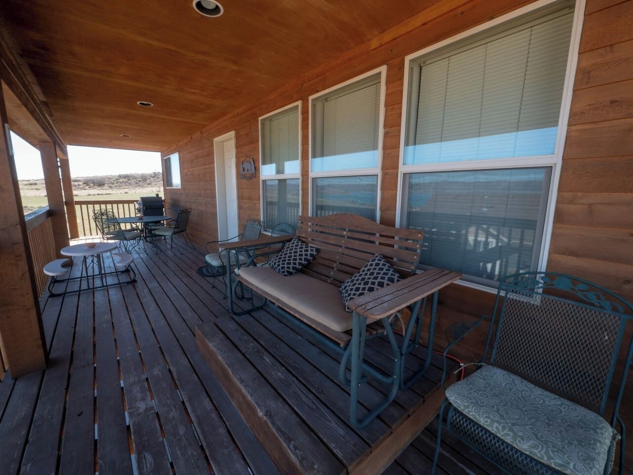 Une terrasse en bois avec un banc, des chaises et une table.