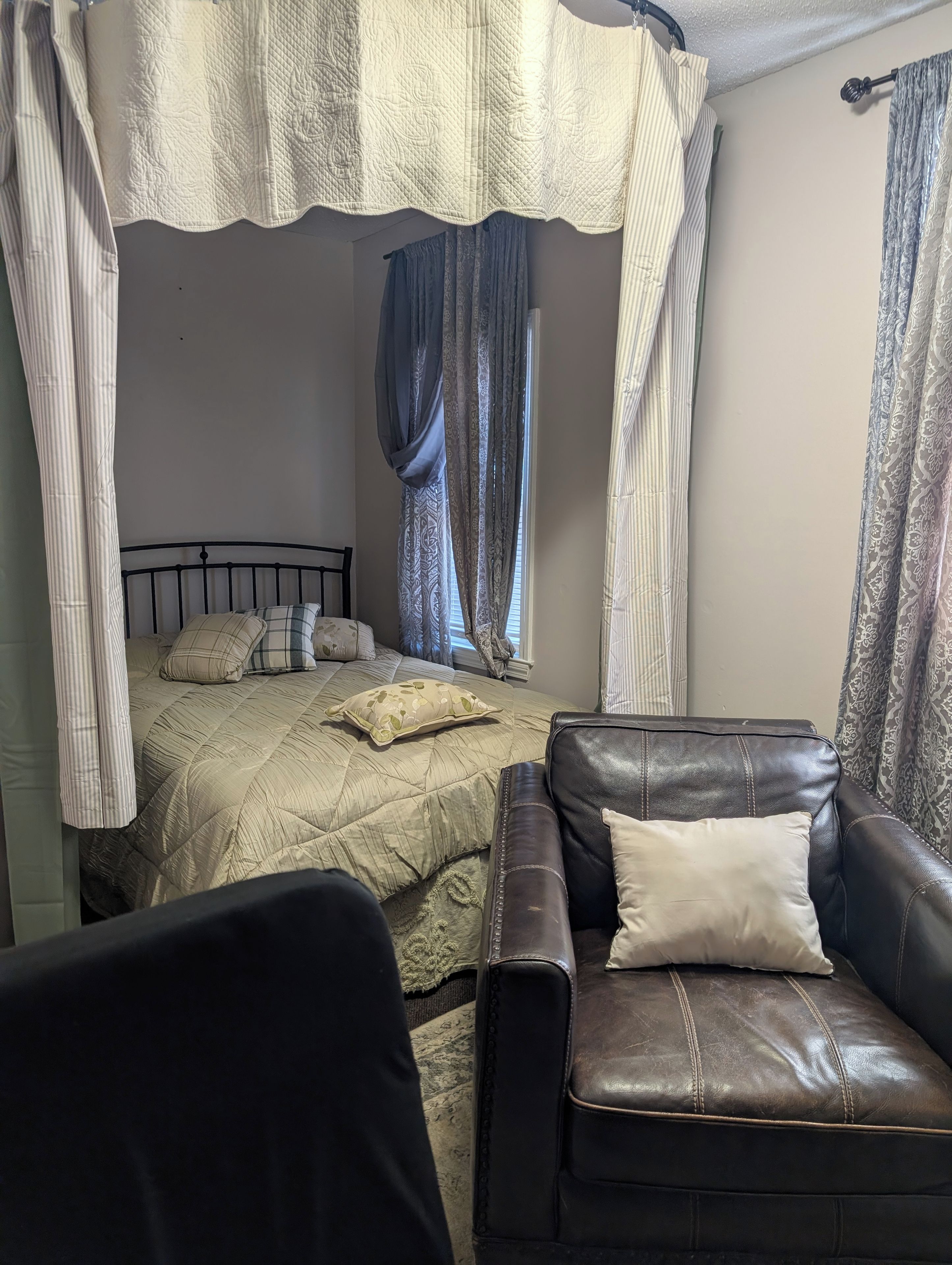 Un dormitorio con cama, sofá de cuero y dosel.