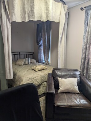 A bedroom with a bed, a leather sofa, and a canopy bedspread. - 146-3 The Duke. The Master Artist.  A 1-bedroom studio. (New London)