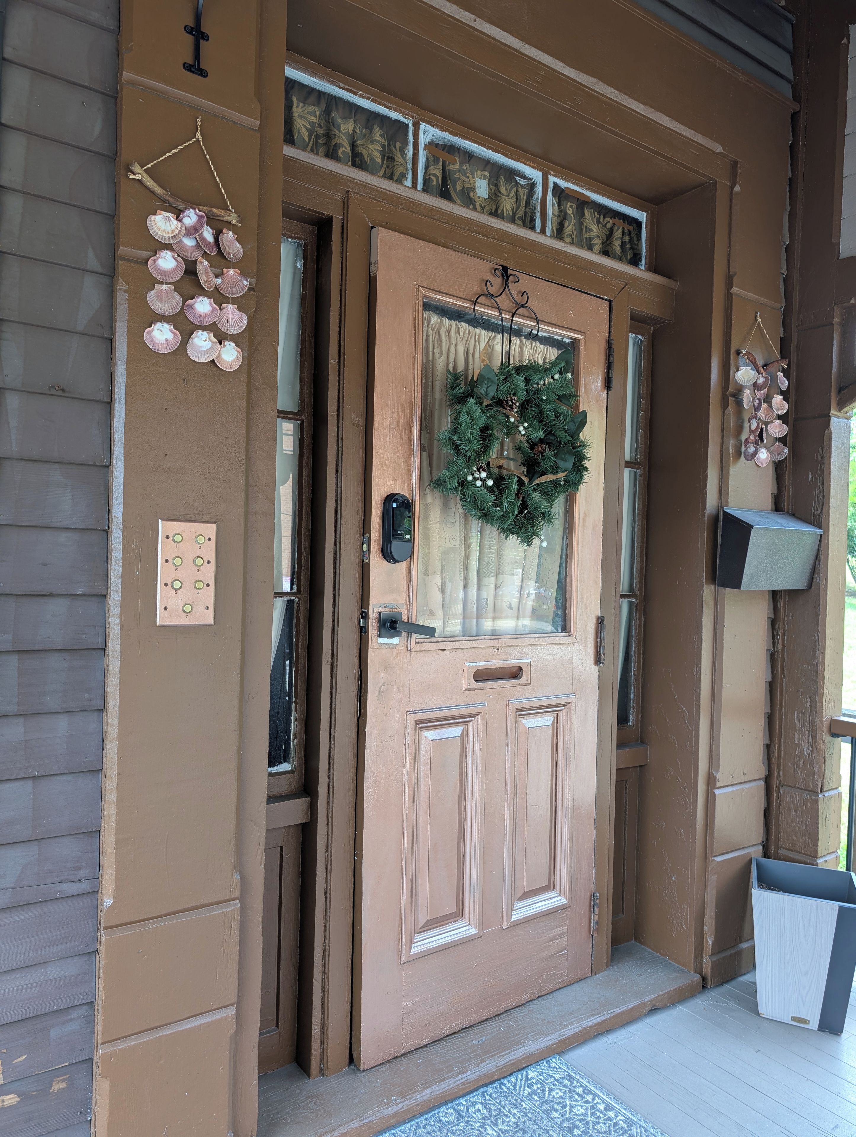 A brown door with a wreath, a mailbox, and a doorbell.