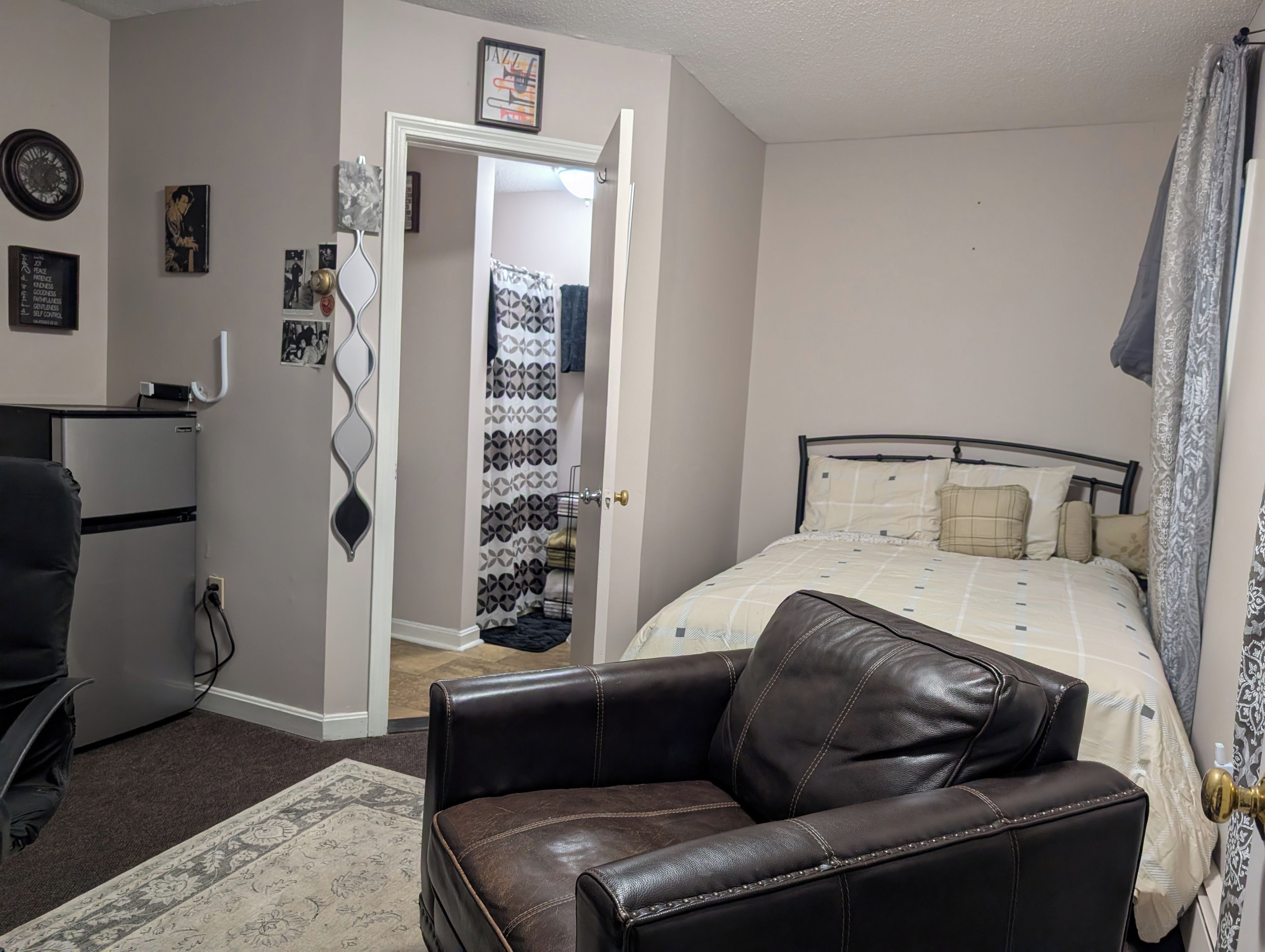 A bedroom with a bed, a chair, a desk, and a wardrobe.