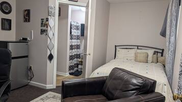 A bedroom with a bed, a chair, a desk, and a wardrobe.