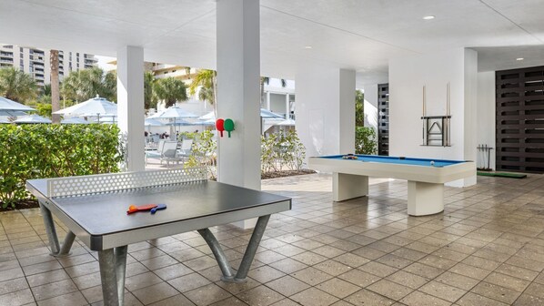 An outdoor recreational area with a ping pong table and a pool table.