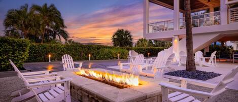 A poolside area with white lounge chairs and a fire feature.