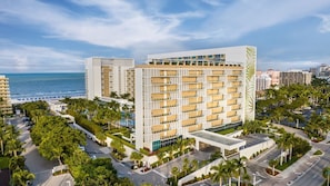A modern hotel with multiple floors, balconies, and a view of the ocean.