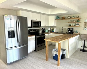 A modern kitchen with stainless steel appliances, white cabinetry, and a wooden island. - Tranquil 2-bedroom waterfront house in charming Matlacha (Matlacha)