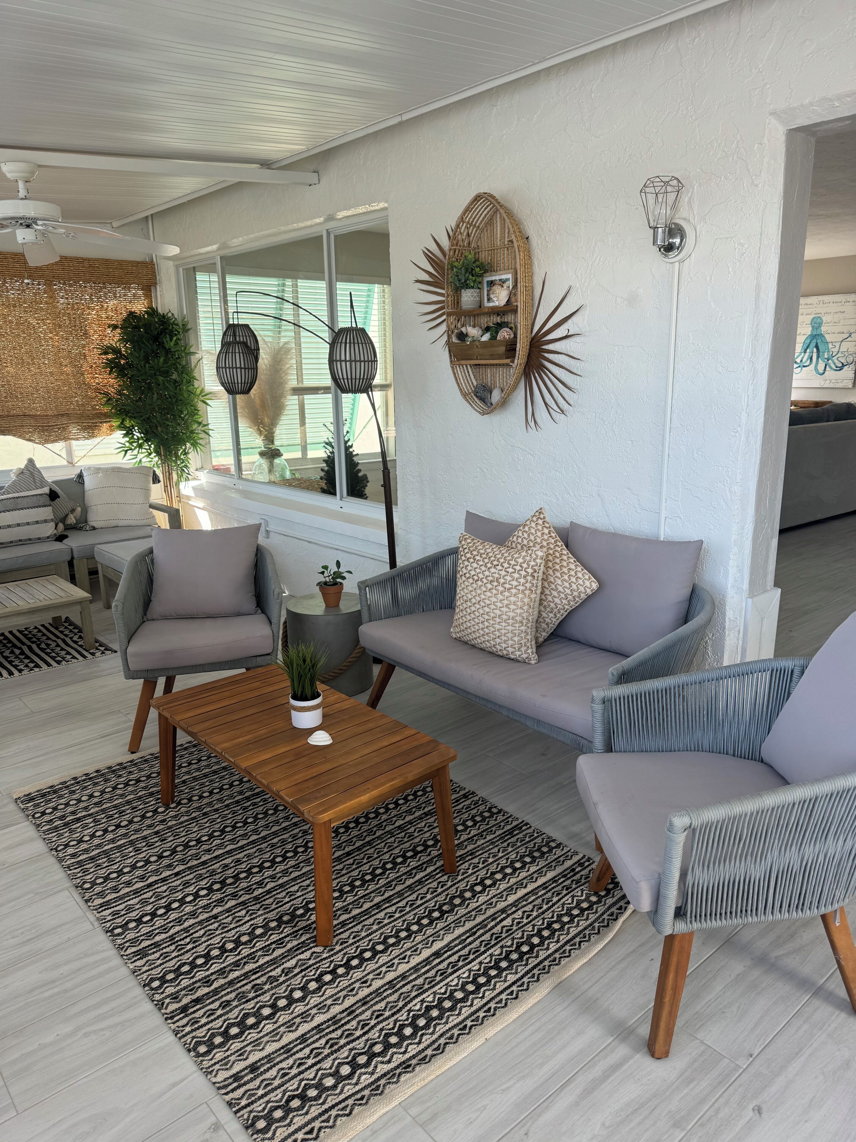 Uma sala de estar moderna com um sofá cinzento, uma mesa de centro de madeira e um tapete estampado.