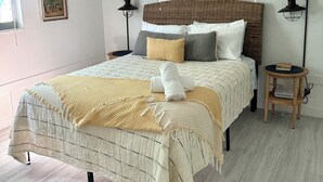 Quarto com cama, ventilador de teto, janela com persianas, luminária na parede e um pôster.