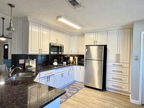 A modern kitchen with white cabinetry, stainless steel appliances, and a granite countertop. - Rest Haven - Cozy, 2 bedroom Townhome (Spring)