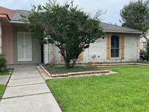A residential house with a brick exterior, a front door with a mailbox, and a small tree in the front yard. - Rest Haven - Cozy, 2 bedroom Townhome (Spring)