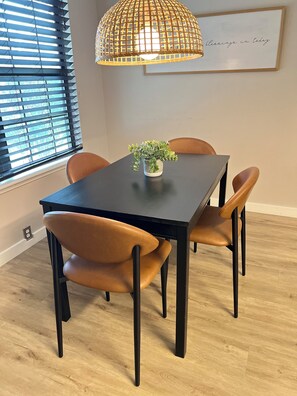 A dining table with chairs, a potted plant, and a hanging light fixture. - Rest Haven - Cozy, 2 bedroom Townhome (Spring)
