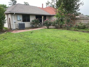 A residential house with a sloped roof, a front yard with grass, and a wooden fence. - Rest Haven - Cozy, 2 bedroom Townhome (Spring)