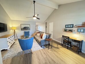 Ein modernes Wohnzimmer mit blauem Sessel, einer Couch, einem Couchtisch und einem Deckenventilator.