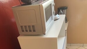 A kitchen with a stove, microwave, and a coffee maker on the counter.