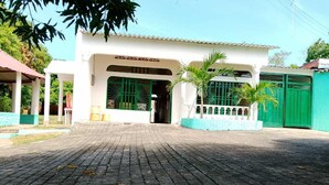 A paved entrance to a building with a covered walkway, a green gate, and a white building facade. - Girardot Vacation Rental: Your Relaxation Guaranteed (Cundinamarca)