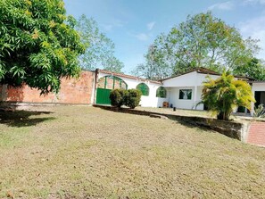 A residential property with a brick wall, a white building with a tiled roof, and a grassy yard.