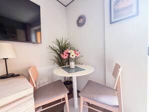 A corner room with a round table, two chairs, a lamp, a clock, and a framed picture on the wall. - Sophisticated Maho Studio with Resort-Style Amenities in a Gated Community. (Maho)