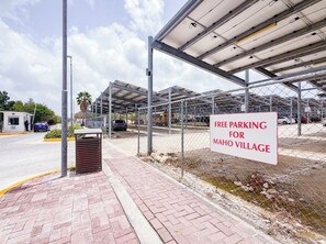 A parking area with a sign indicating free parking at Maho Village. - Sophisticated Maho Studio with Resort-Style Amenities in a Gated Community. (Maho)