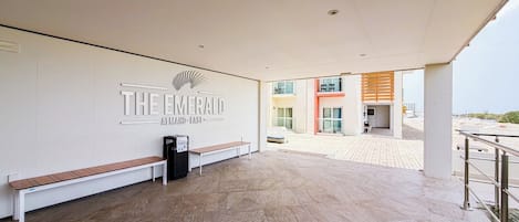 A reception area with a bench, a trash bin, and a wall with the hotel's name.