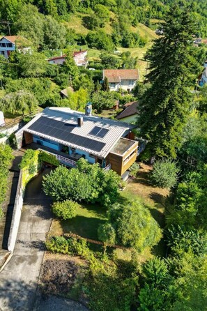 A modern house with a solar panel roof, surrounded by lush greenery and a small pond. - Le Bi-Fûts - ALLEVARD (ALLEVARD)