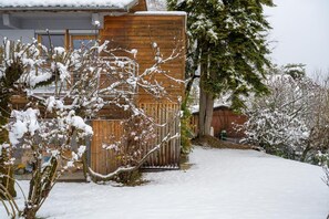 Ein Holzgebäude mit verschneitem Dach und einem verschneiten Weg, der davorhin führt.