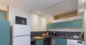 Eine kleine Küche mit Kühlschrank, Mikrowelle, Spüle und Geschirrspüler.