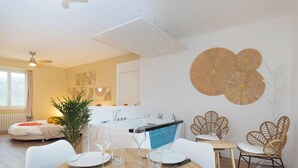 Moderni keittiö, jossa on keskeinen saareke, valkoiset kaapit ja ruokailutila, jossa on valkoiset tuolit ja pöytä.