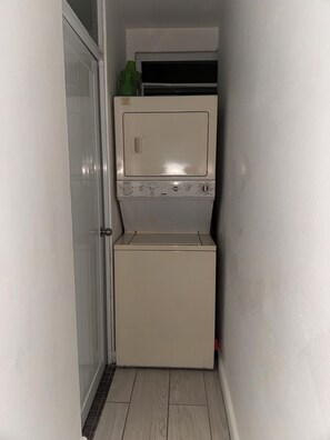 A laundry room with a washing machine and dryer, a door, and a tiled floor. - Casa Patriota (Lares)