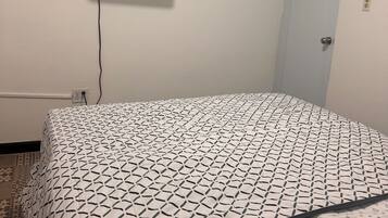 Ein Schlafzimmer mit einem Bett, einem an der Wand befestigten Fernseher und einer Tür.