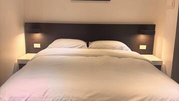 A neatly made bed with a headboard, two bedside tables with lamps, and a framed picture on the wall.