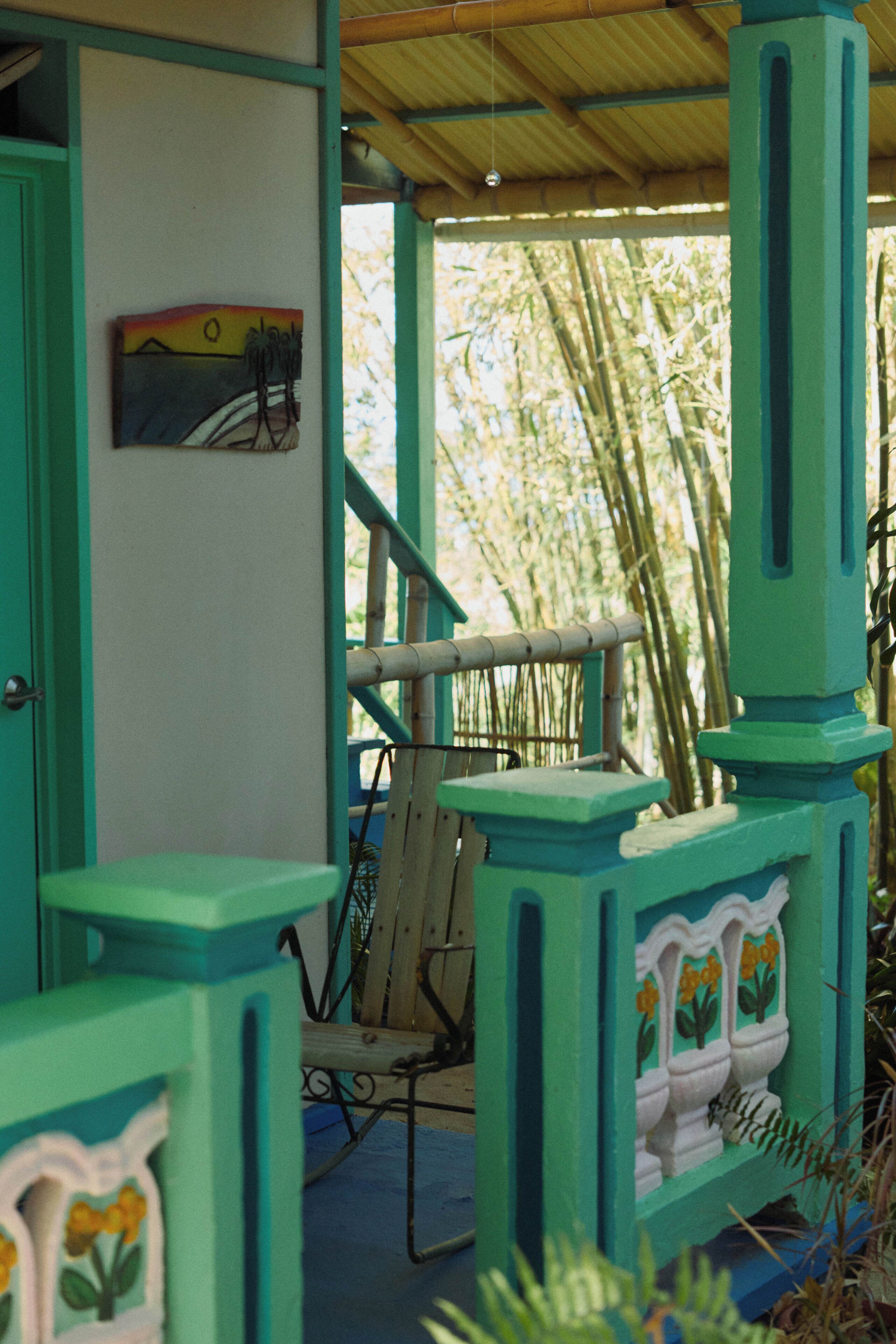 A room with a bamboo backdrop, a chair, and a door with a painting.