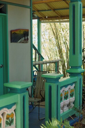 A room with a bamboo backdrop, a chair, and a door with a painting. - Casa de Bambu (Rincón)
