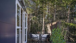 A deck with a table and chairs, surrounded by a forest. - Quiet and Private Tiny Home with Outdoor Bath in Hanmer Springs (Hanmer Springs)