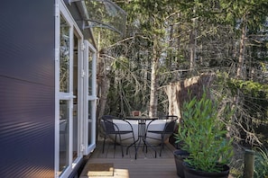 A deck with a table and chairs, surrounded by a forest.