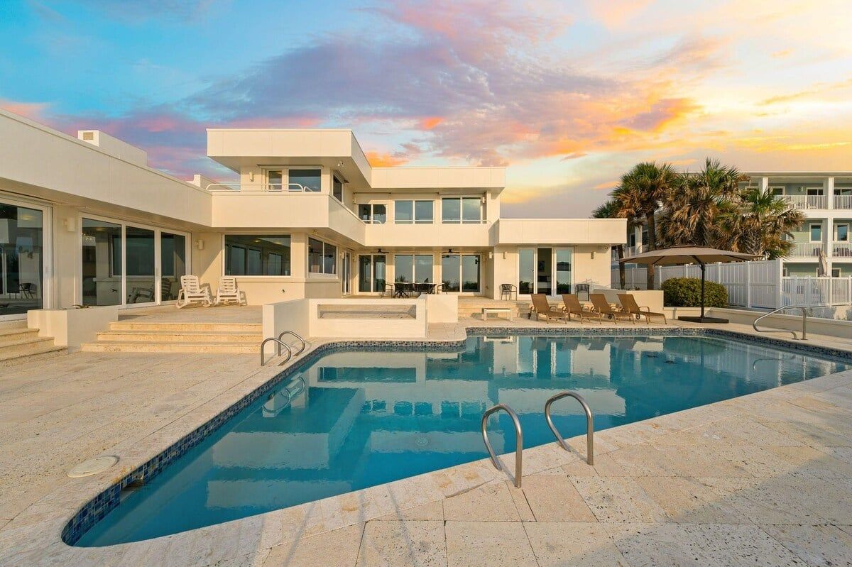 A modern pool area with a clear sky and a sunset.