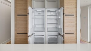 Eine moderne Küche mit einem eingebauten, doppeltürigen Kühlschrank, Holzschränken und einer weißen Arbeitsplatte.