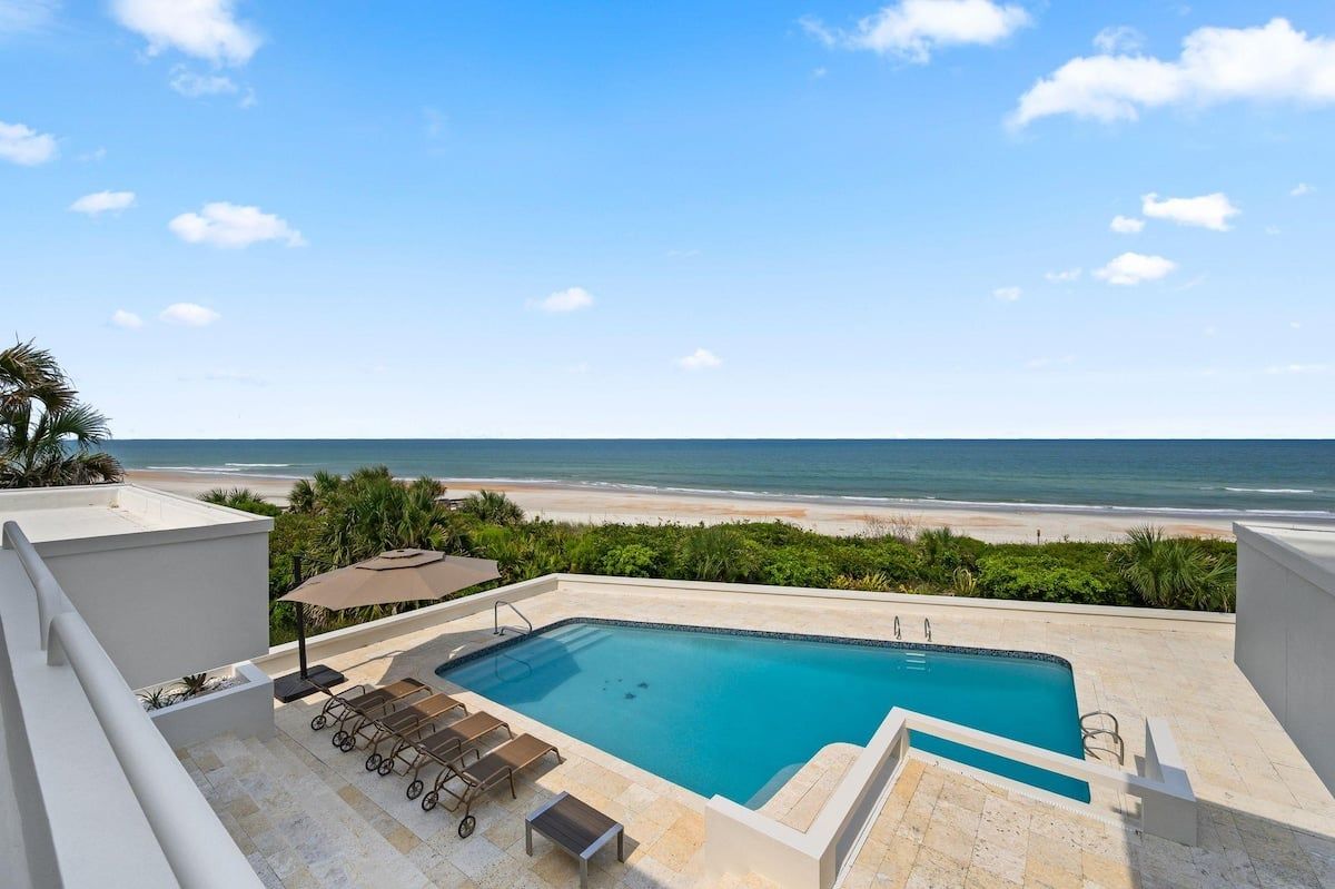 A rooftop pool with a view of the beach and ocean.