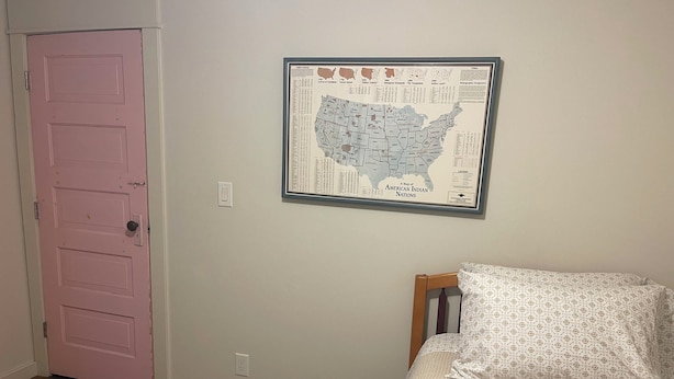 Ein Schlafzimmer mit einem Bett, einer rosafarbenen Tür und einer gerahmten Karte an der Wand.