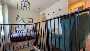 Ein modernes Interieur mit einem Bett, einem grünen Sessel und einer Treppe mit Geländer.