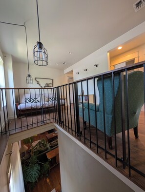 Ein modernes Interieur mit einem Bett, einem grünen Sessel und einer Treppe mit Geländer.